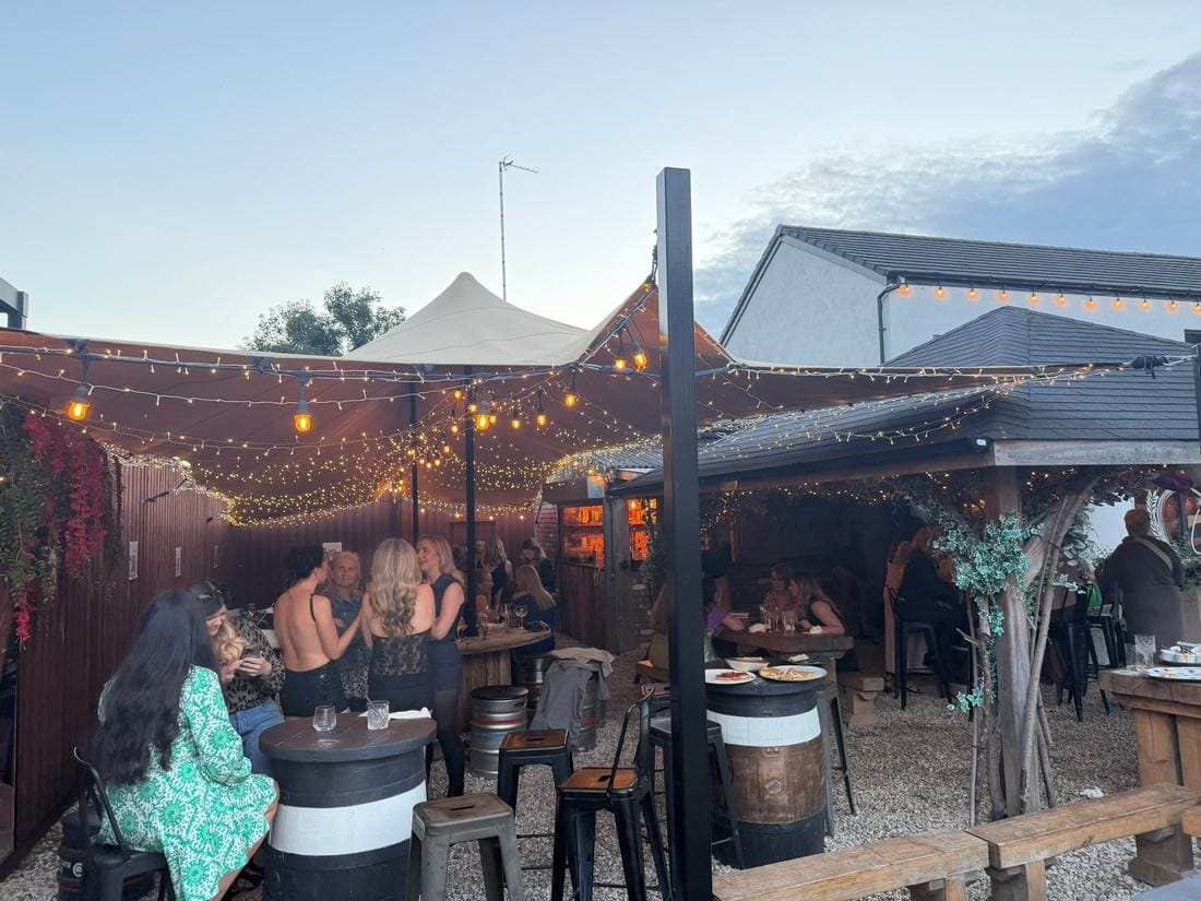 The marquee and pergola lit up with string lights in the evening