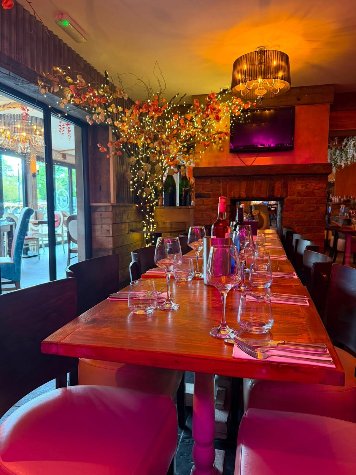 The semi-private dining area: a long table set for a group beneath the autumn blossom and fairy lights