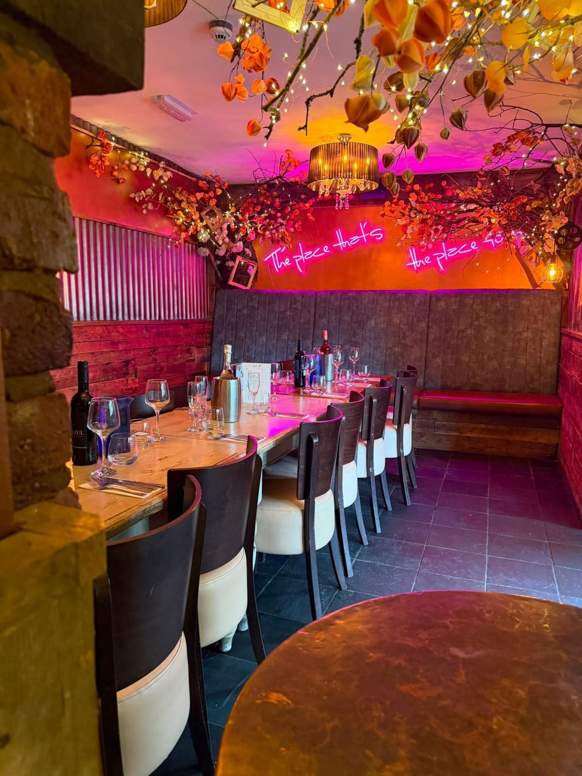 Semi-private dining table laid for guests, with the blossom canopy and canal-side garden beyond